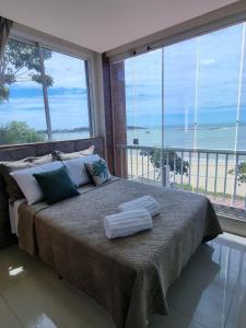 a bedroom with a bed with a view of the ocean at Jequitibá Rosa - frente ao Mar na Praia de Meaípe, Guarapari in Guarapari