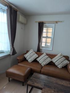 a living room with a brown couch and a window at 1棟貸し Villa YOU hokkaido date toya in Date