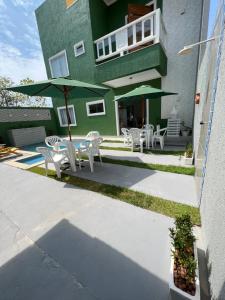 a patio with a table and chairs and an umbrella at Balanço do Mar - Suítes in Prado