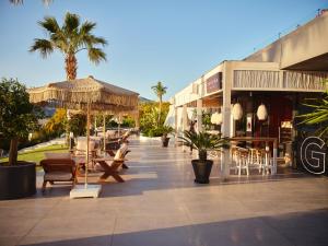 an outdoor patio with tables and chairs and palm trees at Cape Bodrum Luxury Hotel & Beach in Gundogan