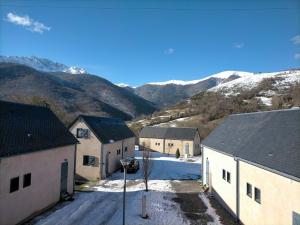 a group of buildings with snowy mountains in the background at Chalet ARREAU in Arreau