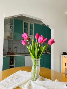 un jarrón lleno de flores rosas sentado en una mesa en casa Felice, en Bitola