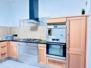 a kitchen with wooden cabinets and a stove top oven at Lovey 6 Bed House Uplands Swansea - Perfect for Families and Contractors in Sketty