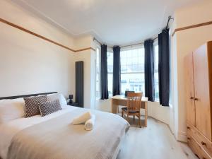 a bedroom with a bed and a desk and window at Lovey 6 Bed House Uplands Swansea - Perfect for Families and Contractors in Sketty +29 photos