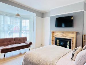 a bedroom with a bed and a fireplace with a flat screen tv at Lovey 6 Bed House Uplands Swansea - Perfect for Families and Contractors in Sketty