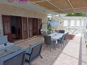 a patio with a table and chairs and a stone wall at Apartman Arijeta Korčula in Smokvica