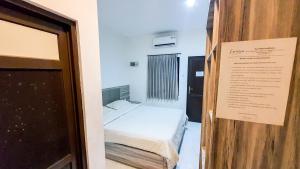 a small room with a bed and a sign on the door at La'Rissa Residence by ARBA in Karawang
