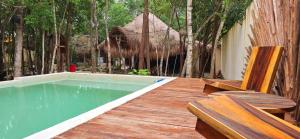 eine Holzterrasse mit Swimmingpool und zwei Bänken in der Unterkunft Hotel Kin Tulum II in Tulum