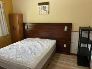 ein Schlafzimmer mit einem Bett und einem hölzernen Kopfteil in der Unterkunft Casa temporada Angra e Paraty in Angra dos Reis