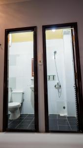 2 espejos en el baño con aseo y ducha en Hue Central Backpacker Hostel, en Hue