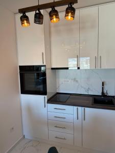 a kitchen with white cabinets and black appliances at Apartman Nikola in Zlatibor +6 photos