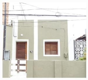 a white house with two windows and a fence at Casa da Lalá in Fortaleza