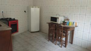une cuisine avec une table et un four micro-ondes. dans l'établissement Casa Edícula Solemar- 3 min da praia, à Praia Grande