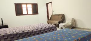 une chambre avec un lit, une chaise et une fenêtre dans l'établissement Casa Edícula Solemar- 3 min da praia, à Praia Grande