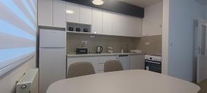 a kitchen with white cabinets and a table and chairs at Apartman Blue Flower Sarajevo in Sarajevo