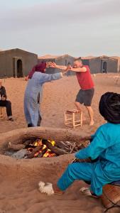 un gruppo di persone intorno ad un fuoco sulla spiaggia di Chigaga Desert Camp a M'Hamid Altre 33 foto