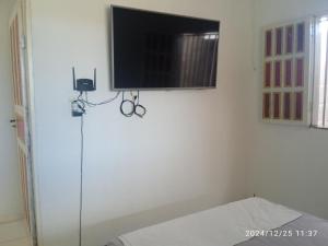 a flat screen tv hanging on a white wall at Mini Recanto da Rosalina in Prado