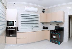 a kitchen with white cabinets and a sink and a stove at Urban Elite Stay in North Legon