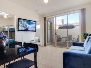 a living room with a blue couch and a tv at McKillop Geelong by Gold Star Stays in Geelong