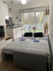 a bedroom with a large bed in front of a kitchen at Le Cosy De l'Ourcq T2 40m2 20 min de Paris in Villepinte