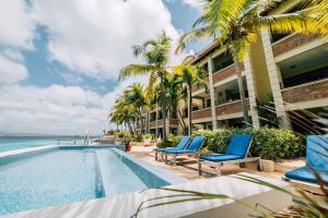 un complejo con piscina y palmeras en The Bellafonte - Luxury Oceanfront Hotel, en Kralendijk