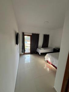 una camera con due letti, una televisione e una finestra di Pousada Juventus a Barra Grande