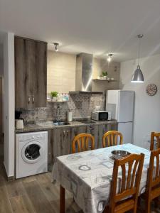 a kitchen with a table and a white appliance at El hondón del lugar 2 in Hoyos