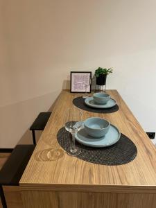 a wooden table with two plates and wine glasses at Apartament Piłsudskiego in Tychy
