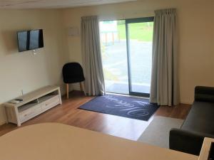 a living room with a couch and a sliding glass door at Otorohanga Kiwi Holiday Park in Otorohanga