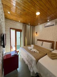 伊卡莱Kanto do Chico Prime的一间卧室，配有两张床和木质天花板