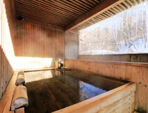 a swimming pool in a wooden house with a window at Kose Onsen in Karuizawa