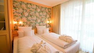2 camas en una habitación con una pared floral en Seeschlößchen - Hotel Strandperle, en Cuxhaven