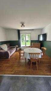 a living room with a table and chairs and a couch at Parenthèse en Terre Breizh in Bohal