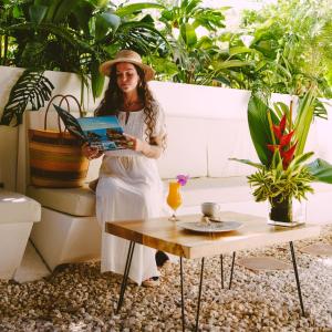 a woman in a hat holding a book in a garden at Hotel Villabosque Eco Boutique in Manuel Antonio