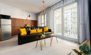 sala de estar con sofá negro y almohadas amarillas en ApartamentyGdansk EU - ŻURAWIE I, en Gdansk