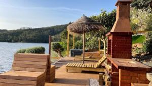 a wooden deck with a gazebo and benches on a lake at Casa da Saudade in Ferreira do Zêzere