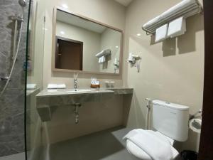 a bathroom with a toilet and a sink and a mirror at Hexton Hotel Lampung by Amazing in Bandar Lampung