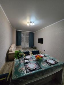 ein Wohnzimmer mit einem Tisch mit Tellern und Obst darauf in der Unterkunft Апартаменты Астаны in Astana
