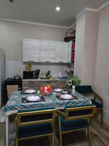 eine Küche mit einem Tisch mit Tellern und Obst darauf in der Unterkunft Апартаменты Астаны in Astana