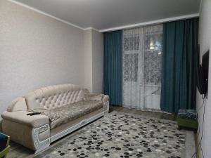 ein Wohnzimmer mit einer Couch und einem Fenster in der Unterkunft Апартаменты Астаны in Astana