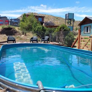 a swimming pool with chairs and a house in the background at Cabaña El Pazo in Sierra de la Ventana