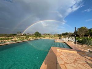 a rainbow in the sky over a swimming pool at Blue Door Mallorca in Caʼs Concos