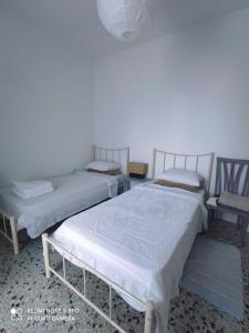 two beds and a chair in a room at to the sea in Anavissos