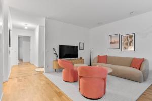 a living room with a couch and two orange chairs at The Pink Patio - Cozy Modern Private Apartment in Solna