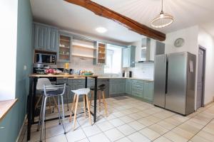 a kitchen with green cabinets and a stainless steel refrigerator at La grange des Thermes in Beaucens