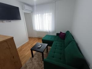 a living room with a green couch and a table at Stan na dan Nina Plus - Pale Centar in Pale