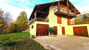 Cette grande maison dispose de portes rouges et d'un balcon. dans l'établissement Chalet Meijoun-pelvoux - Chalet de montagne confortable pour 10 personnes MAE-6831, à Pelvoux