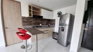 a kitchen with a stainless steel refrigerator and a red stool at Hacienda Peñalisa Bambu Girardot-Ricaurte in Soacha