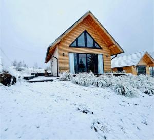 a house with snow on the ground in front of it at Słoneczny Stok in Małastów