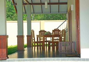 a porch with a table and chairs on it at The Forest Chalet in Tissamaharama